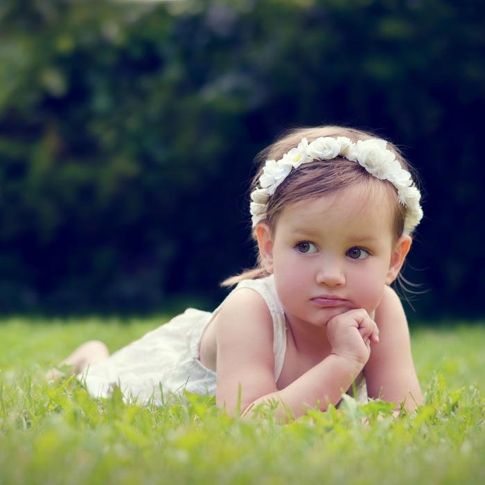 Beautiful baby girl white dress lying grass garden