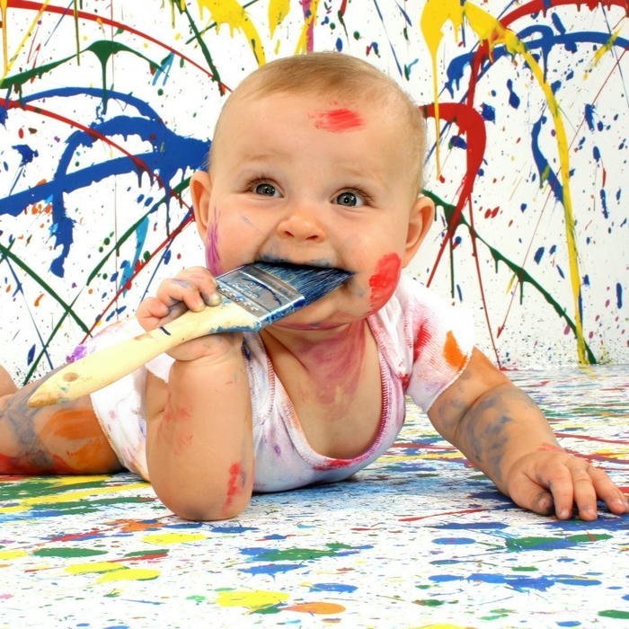 Messy baby covered paint holding brush art fun